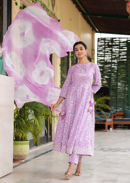 Woman in a lavender traditional outfit with a matching dupatta, standing outdoors.