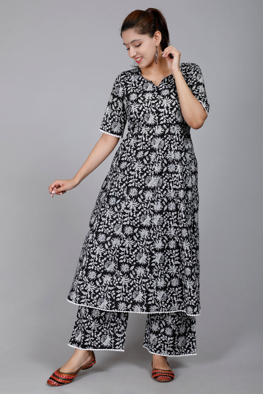 Woman wearing a black and white floral dress and pants on a gray background
