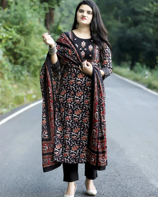 Woman wearing a black and red patterned outfit on a road with greenery in the background