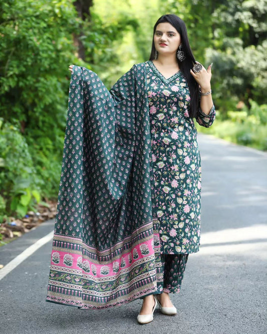 Woman wearing a green floral outfit with a dupatta on a road surrounded by greenery