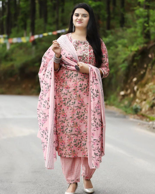 Woman in a pink floral outfit standing on a road with greenery in the background