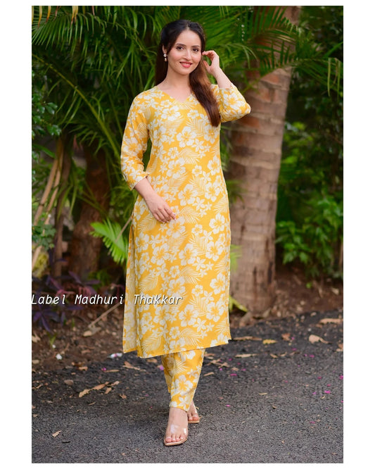Woman wearing a yellow floral kurta with pants standing outdoors.