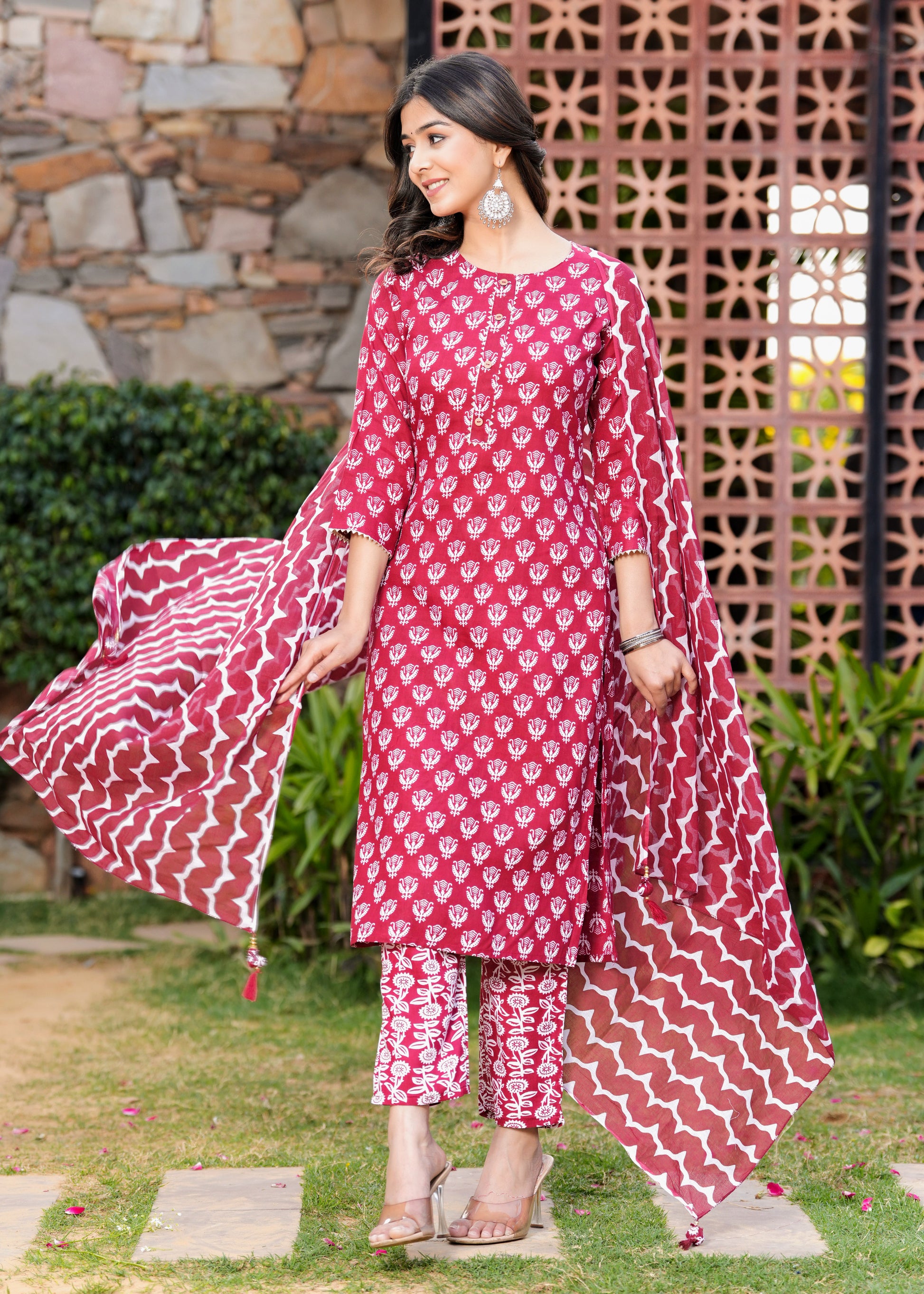 Woman wearing a pink and white patterned traditional outfit in an outdoor setting.