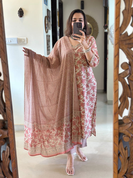 Woman taking a mirror selfie wearing a floral kurta with a dupatta in a home setting.