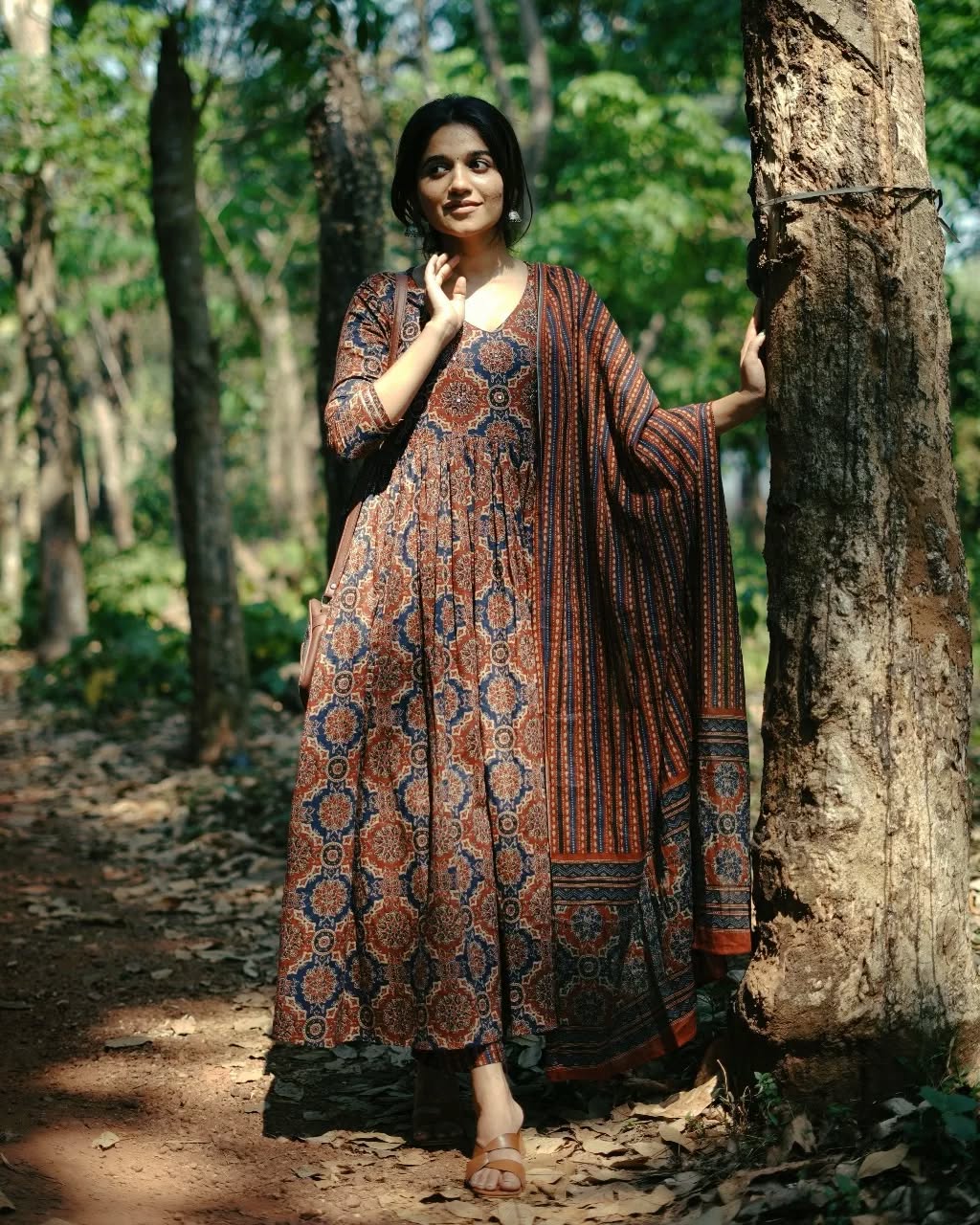 Woman in a patterned dress standing in a forest