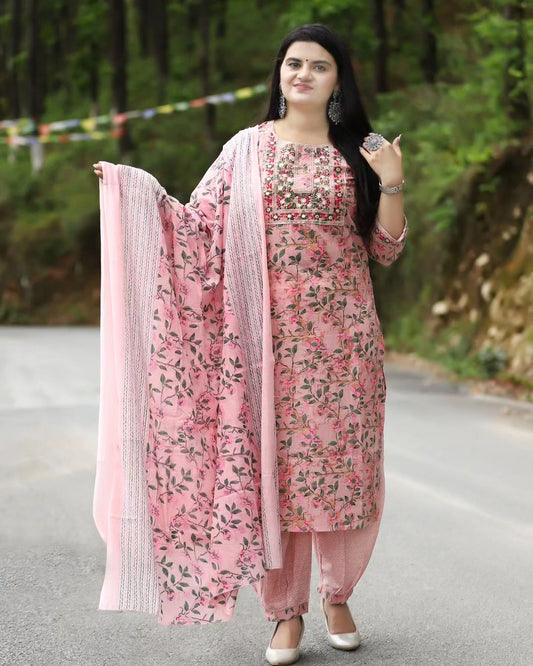 Woman in a pink floral outfit standing on a road with greenery in the background