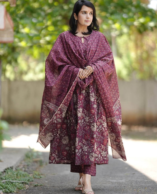 Woman wearing a patterned shawl outdoors with greenery in the background