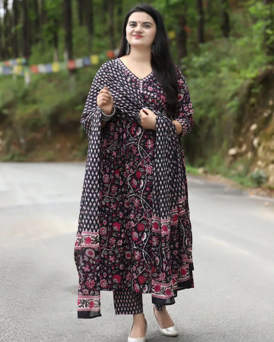 Woman in a floral dress standing on a road with a forest background